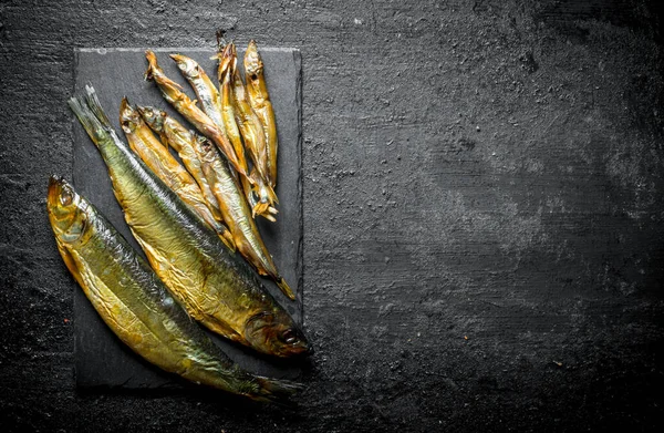 Taş tahtada farklı füme balıklar. Siyah rustik arka plan üzerinde