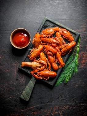 Sos ve dereotu ile kesme Tahtası üzerinde Haşlanmış kırmızı kerevit. Koyu rustik arka plan üzerinde