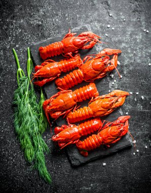 Dereotu ile bir taş tahta üzerinde kokulu haşlanmış kerevit. Koyu rustik arka plan üzerinde