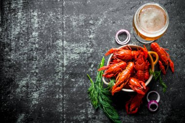 Bira, dereotu ve soğan halkaları ile bir kapta kokulu haşlanmış kerevit. Koyu rustik arka plan üzerinde