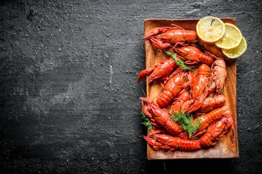 Limon dilimleri ile haşlanmış kerevit. Siyah rustik arka plan üzerinde