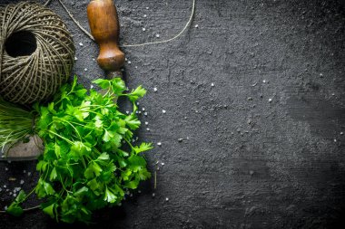 Taze maydanoz, eski ip ve bıçak. Siyah rustik arka plan üzerinde