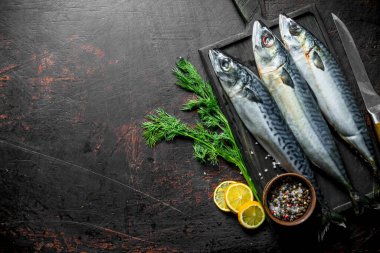 Limon, dereotu ve baharat dilimleri ile bir kesme Tahtası üzerinde Balık uskumru. Koyu rustik arka plan üzerinde