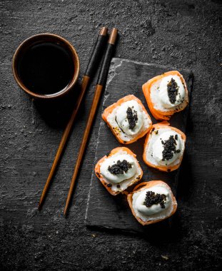 Somon, krem peynir ve havyar ile taze rulo. Siyah rustik arka plan üzerinde