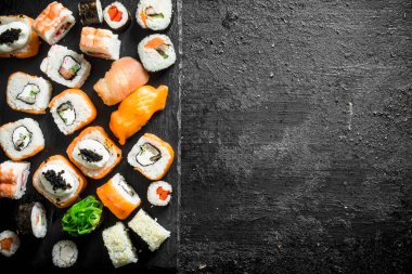Somon, tavuk, karides ve sebze ile farklı suşi rulo ayarlayın. Siyah rustik arka plan üzerinde