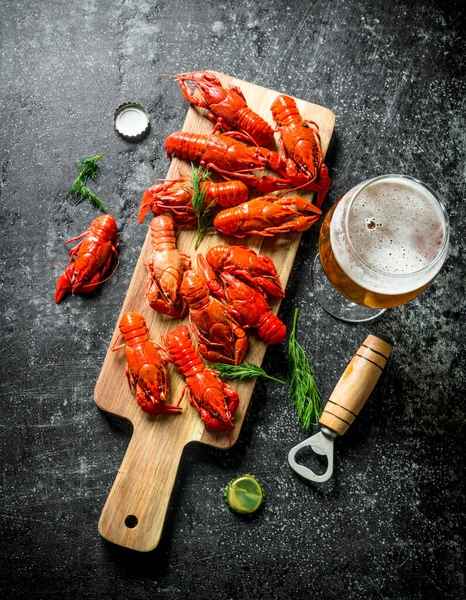 stock image Red boiled crayfish on a cutting Board with beer. On dark rustic background