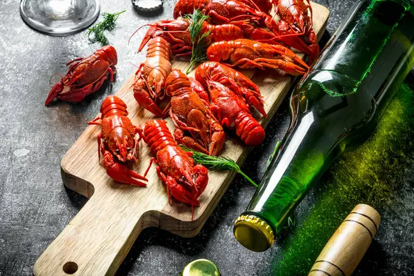 stock image Boiled crayfish with a bottle of beer. On dark rustic background