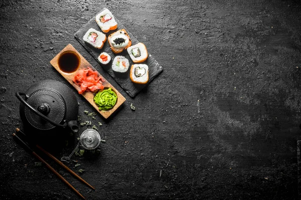 美味的卷与鲑鱼和蔬菜在石板与酱油在碗 在黑色质朴的背景 — 图库照片