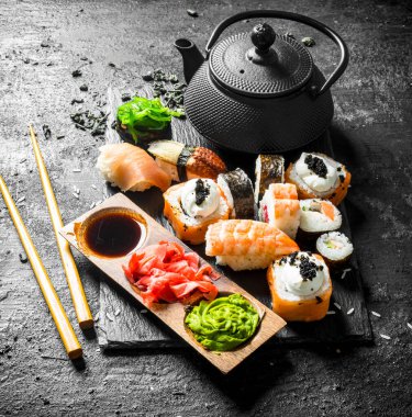 Soya sosu ve zencefil ile bir taş Kurulu Japon deniz ürünleri suşi. Siyah rustik arka plan üzerinde