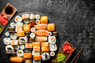 Sos ve çubuklar ile Lezzetli Japon rulo. Koyu rustik arka plan üzerinde