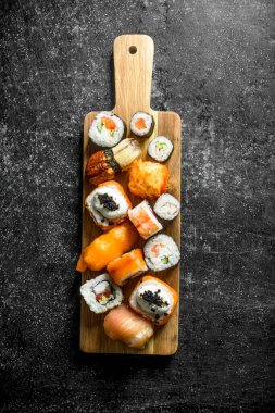 Bir kesme Tahtası üzerinde taze pişmiş suşi rulo. Koyu rustik arka plan üzerinde