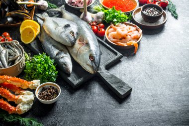 Karides, yengeç ve otlarla taze balık. Koyu rustik arka plan üzerinde