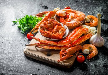 Taze pişmiş kerevit, yengeç ve otlar ile karides. Koyu rustik arka plan üzerinde