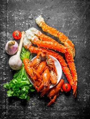 Deniz ürünleri. Pişmiş kerevit ve sarımsak, maydanoz ve domates ile yengeç. Koyu rustik arka plan üzerinde