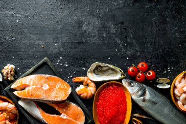 Kesme tahtasında somon yığını var. Siyah rustik arka plan üzerinde