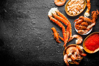 Deniz ürünleri. Pişmiş kerevit, karides, kırmızı havyarlı yengeç. Siyah rustik arka plan üzerinde