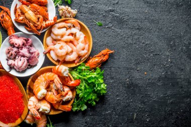 Çeşitli deniz ürünleri ile kırmızı havyar. Siyah rustik arka plan üzerinde