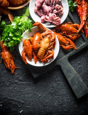 Kesme Tahtası'nda taze sağlıklı deniz ürünleri. Siyah rustik arka plan üzerinde