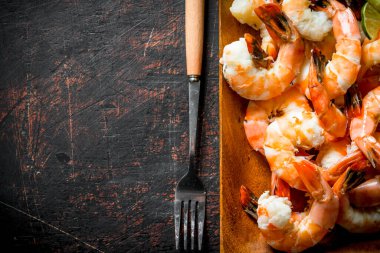 Çatallı tahta bir tabakta kokulu karidesler. Koyu rustik arka plan üzerinde