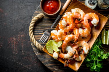 Maydanoz ve domates soslu tepside pişmiş karides. Koyu rustik arka plan üzerinde