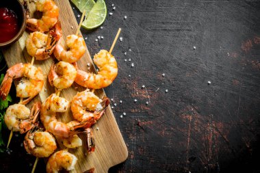 Soslu kesme tahtasında kızarmış karides. Koyu rustik arka plan üzerinde