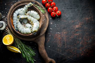 Baharatlı, domatesli ve limonlu bir tabakta çiğ karides. Koyu kırsal arkaplanda