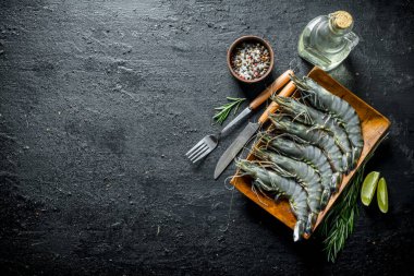 Limon dilimleri, biberiye ve baharatile çiğ karides. Siyah rustik arka plan üzerinde