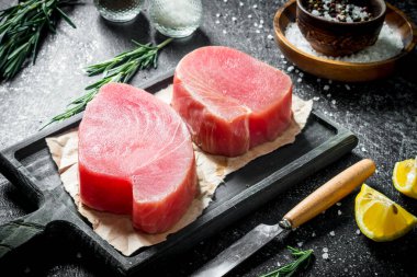 Baharat ve biberiye ile kesme Tahtası üzerinde ham ton balığı fileto. Koyu rustik arka plan üzerinde