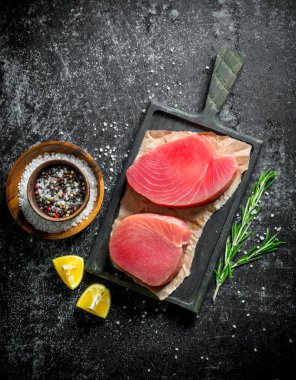 Biberiye, limon ve baharatile kesme Tahtası üzerinde ham ton balığı fileto. Koyu rustik arka plan üzerinde