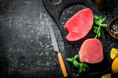 Nane, limon ve baharatile kesme Tahtası üzerinde ham ton balığı fileto. Koyu rustik arka plan üzerinde