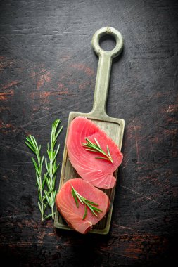 Biberiye ile kesme Tahtası taze çiğ ton balığı biftek. Koyu rustik arka plan üzerinde