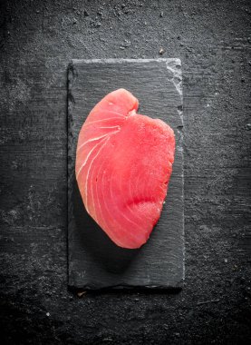 Taş tahtada çiğ ton balığı bifteği. Siyah rustik arka plan üzerinde