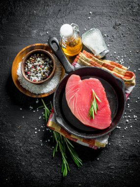 Biberiye ve baharat ile bir peçete üzerinde bir tavada taze çiğ ton balığı. Siyah rustik arka plan üzerinde