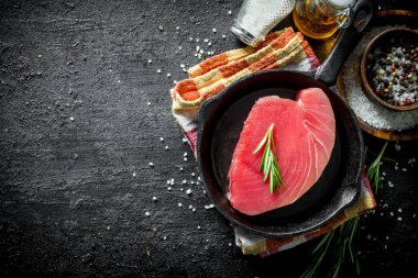 Biberiye ve baharat ile bir peçete üzerinde bir tavada taze çiğ ton balığı. Siyah rustik arka plan üzerinde