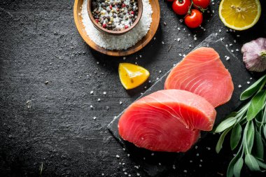 Domates, baharat ve limon ile taze çiğ ton balığı parçaları. Siyah rustik arka plan üzerinde