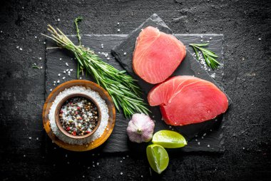 Biberiye, sarımsak, limon ve baharat ile çiğ ton balığı. Siyah rustik arka plan üzerinde