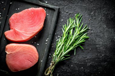 Bir demet biberiyeli çiğ ton balığı. Siyah rustik arka plan üzerinde