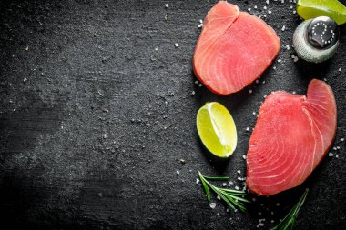 Baharat ve kıyılmış kireç ile çiğ ton balığı parçaları. Siyah rustik arka plan üzerinde