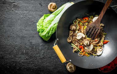 Wok tavada kokulu soba eriştesi. Siyah rustik arka plan üzerinde