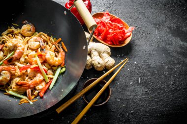 Zencefilli Wok Udon eriştesi, soya sosu ve dolmalık biber. Siyah kırsal arkaplanda
