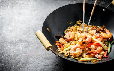 Çin wok. Karides ve sos ile bir wok tavada Udon erişte. Koyu rustik arka plan üzerinde