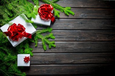 Yeşil köknar dalları olan beyaz Noel kutuları. Koyu bir ahşap arka planda