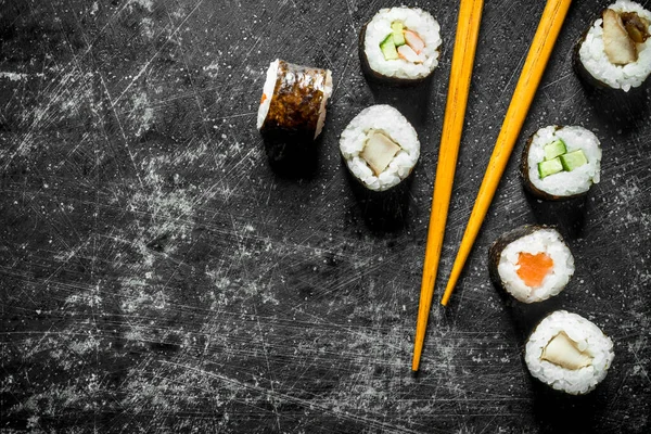 stock image Sushi rolls with wooden chopsticks. On dark rustic background