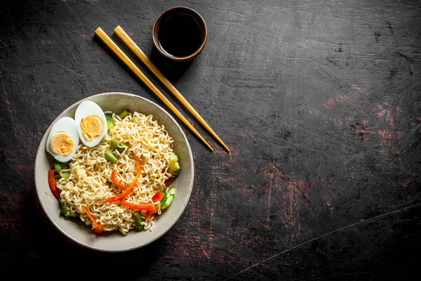 Stock image Instant noodles with vegetables and a sliced egg. On dark rustic background