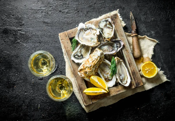 stock image Delicious raw oysters with white wine in glasses. On black rustic background