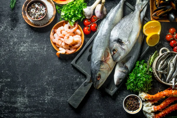 Karides, yengeç ve otlarla taze balık. Koyu rustik arka plan üzerinde