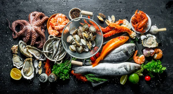 stock image Variety of fresh seafood with herbs and lime. On black rustic background