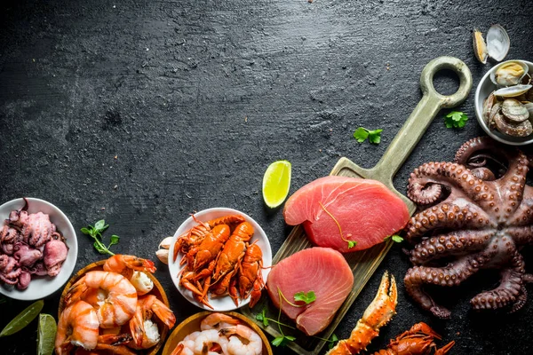 stock image Seafood. Fresh tuna steak with octopus, shrimp, crayfish and oysters. On black rustic background