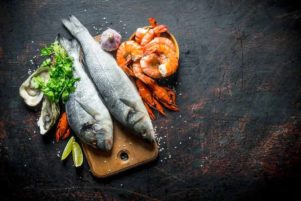 Fresh fish on a cutting Board with oysters, shrimp and crayfish. On dark rustic background