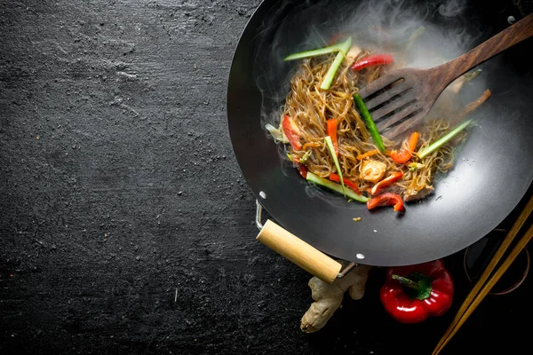 stock image Hot wok Chinese cellophane noodles in a pan with a spatula. On black rustic background